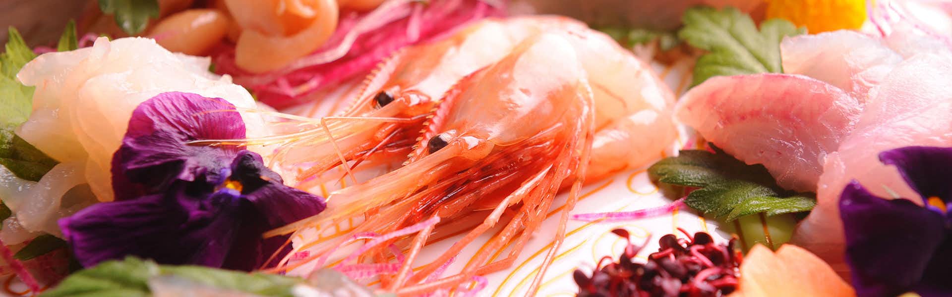 Oyado Ikegami Raw crustaceans with translucent orange shells, curved bodies, antennae, glossy wet surface, pale and magenta-toned elements.