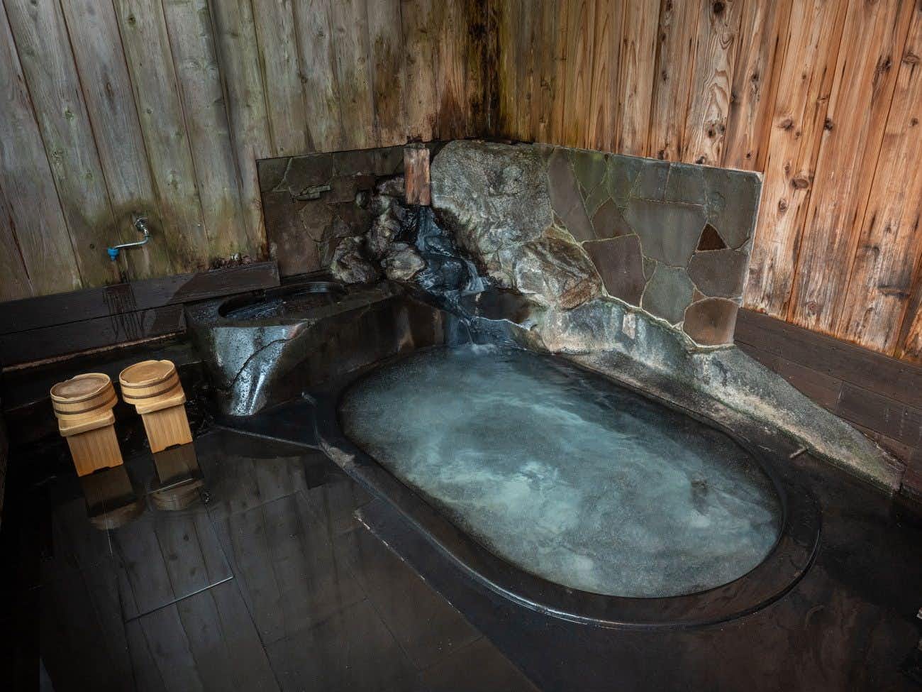 Shirabu Onsen Higashiya small stone-lined indoor bath with wooden buckets