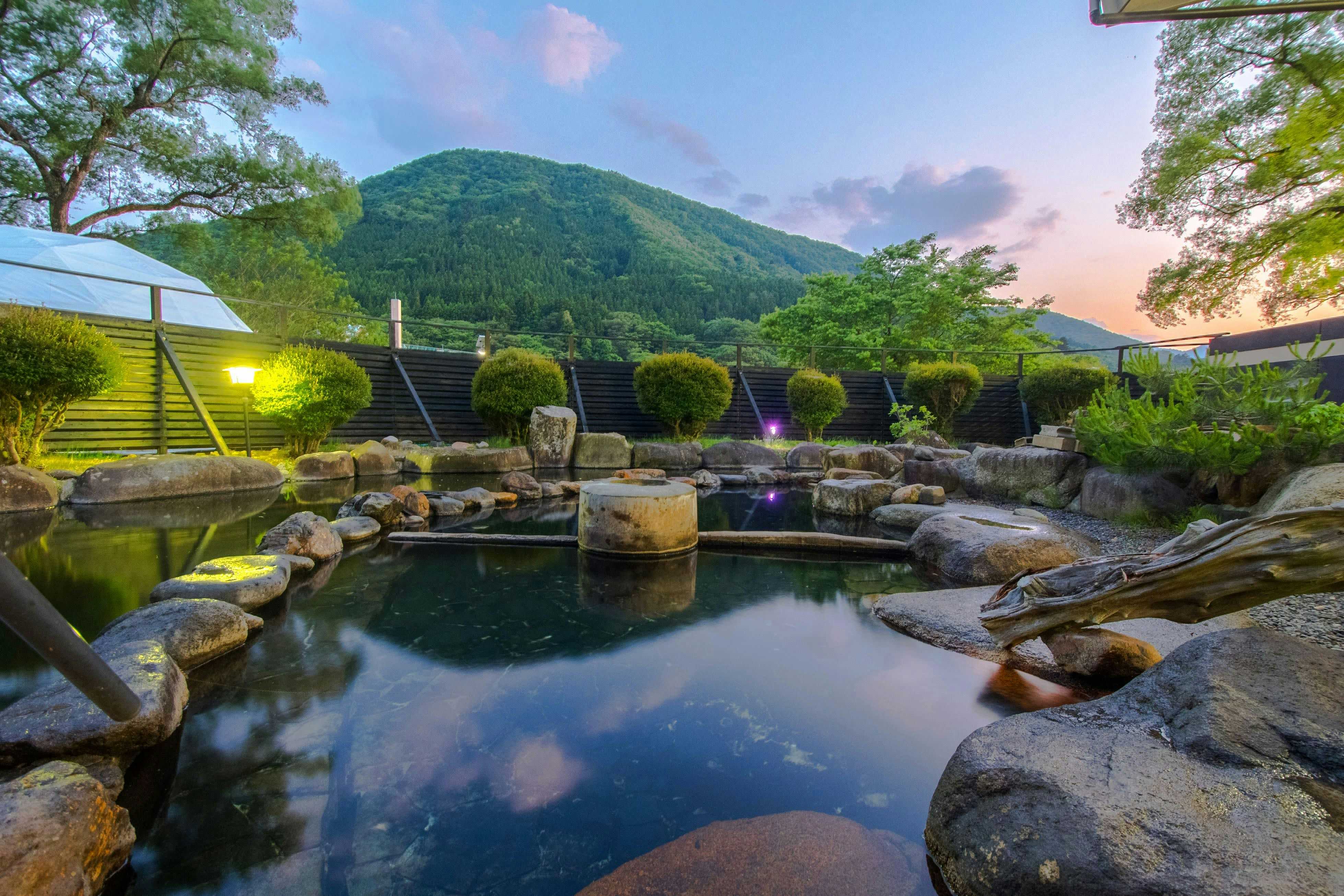 Akasawa Onsen Ryokan with a landscaped pond reflecting mountains and evening sky.