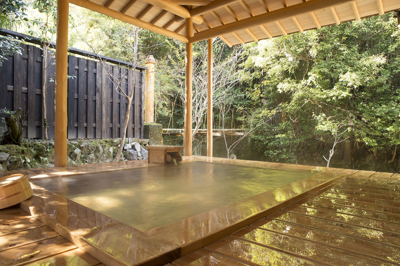 Covered outdoor bath beside a forest.