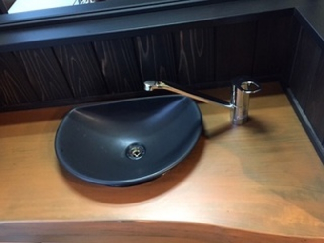 A dark bowl-shaped washbasin on a timber counter.