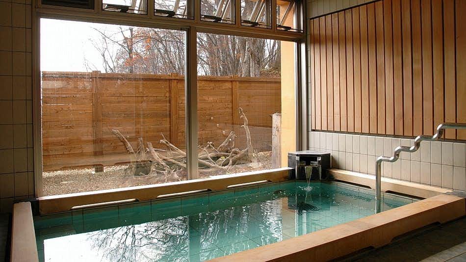 Gassan Shizu Onsen Ryokan Sendai-ya with a rectangular indoor bath beside broad windows and timber screens.