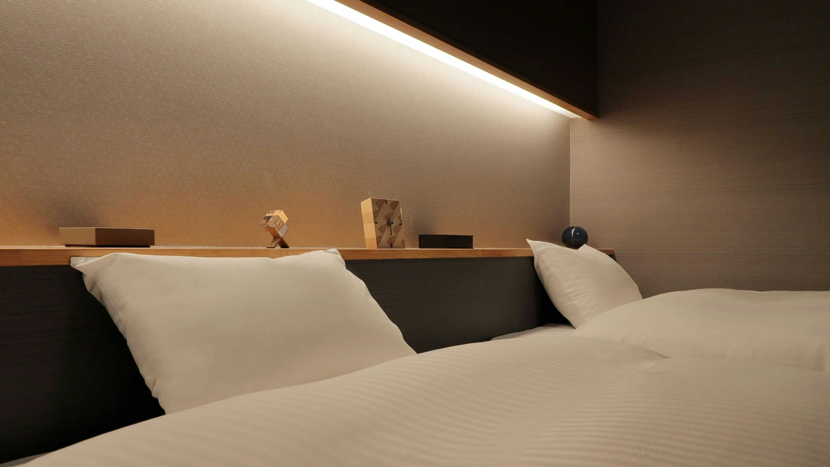 Bandai Atami Onsen Yunoyado Rakuzan with white bedding, dark headboard, wall lights, and beige ceiling