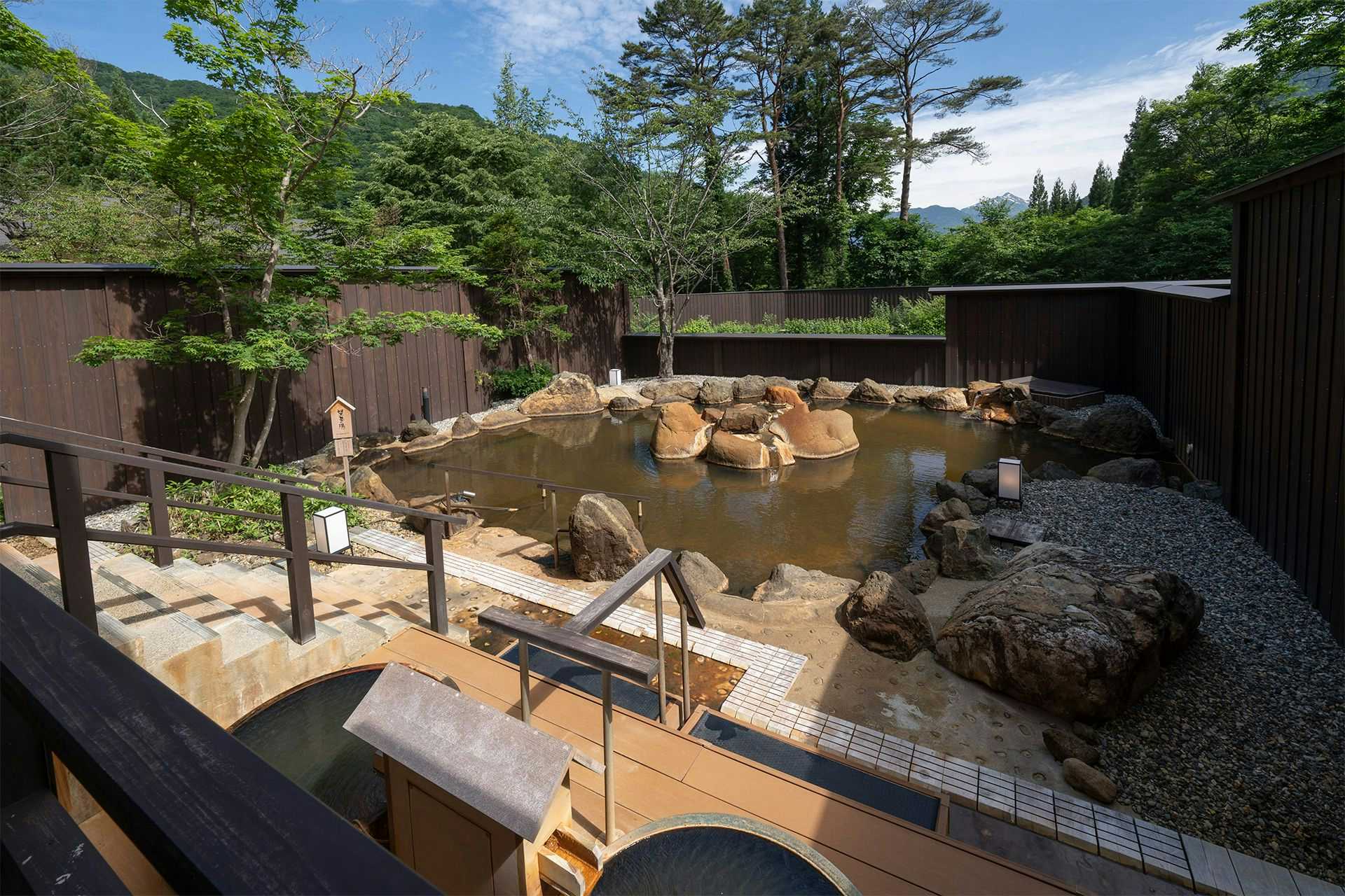 Takumi no Yado Miyama Sakura-an (Kyoritsu Resort) with a rock-lined open-air bath and wooden deck beside the garden.