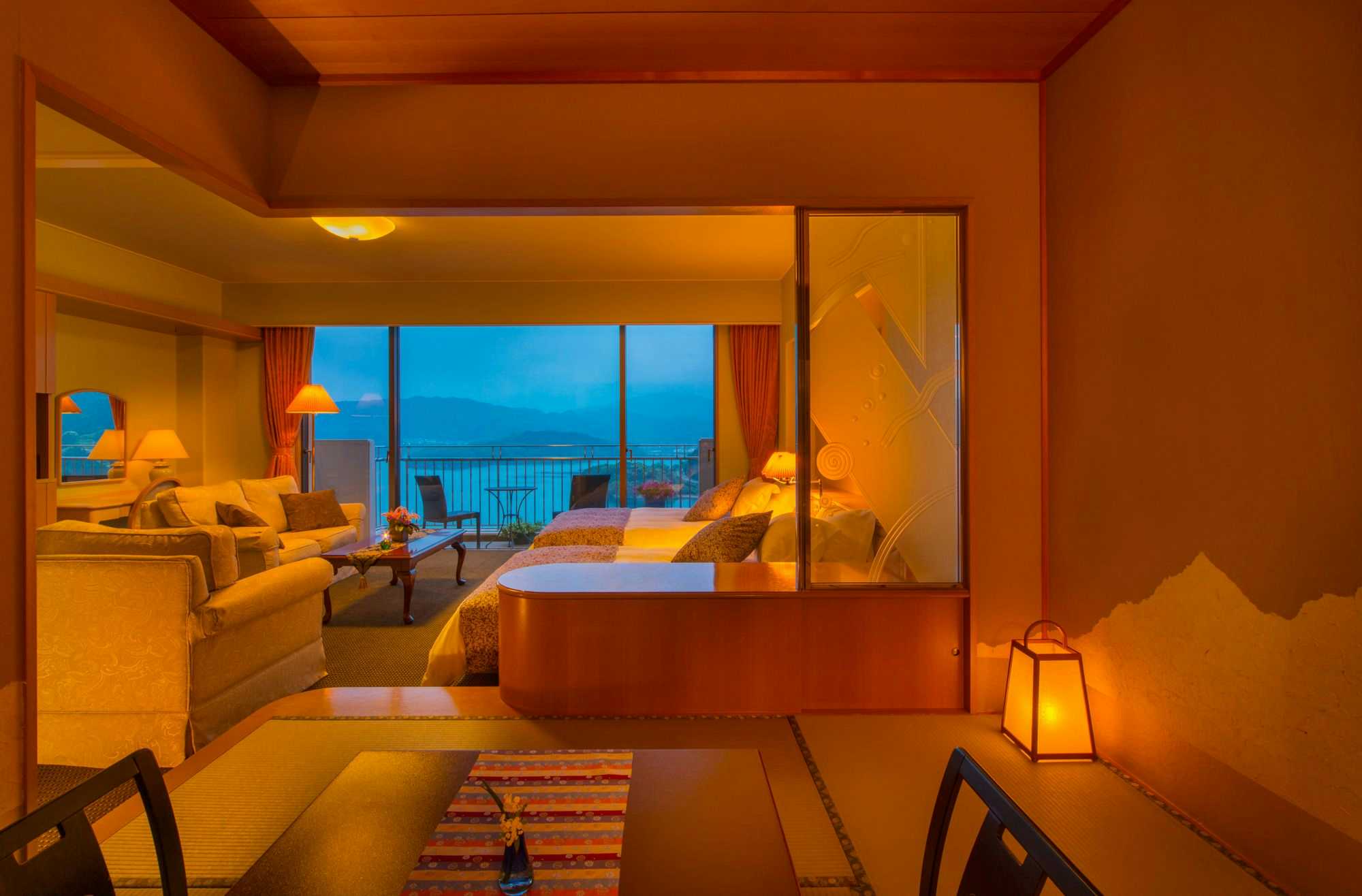 Ryoso Uminocho with this scene, where a warm ocean-facing suite opens from its bed toward a private terrace.