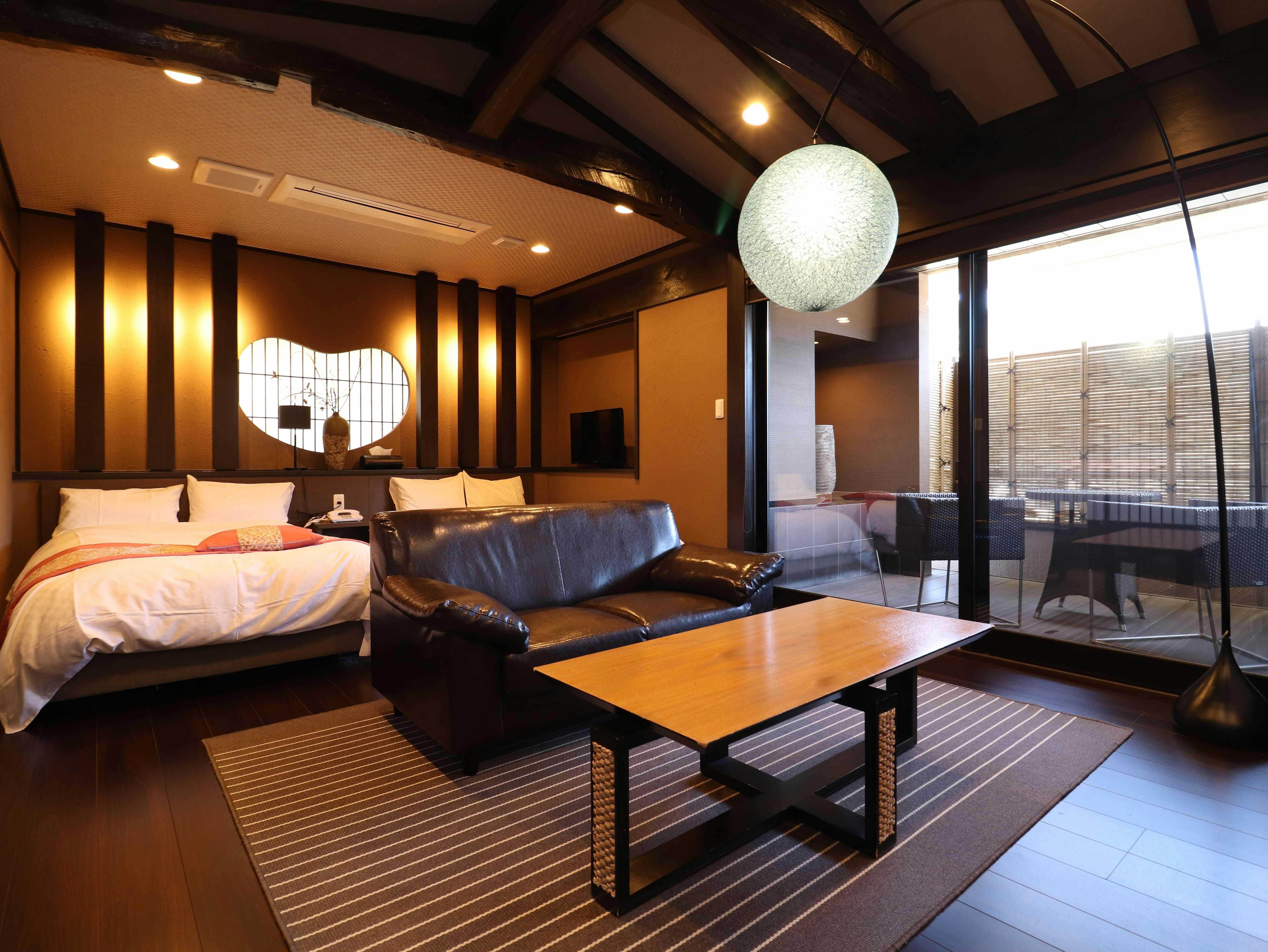 Bokusuisou Toikan Guest room with bed featuring pink bedding, wooden low table, striped rug, dark furniture, and interior window views.