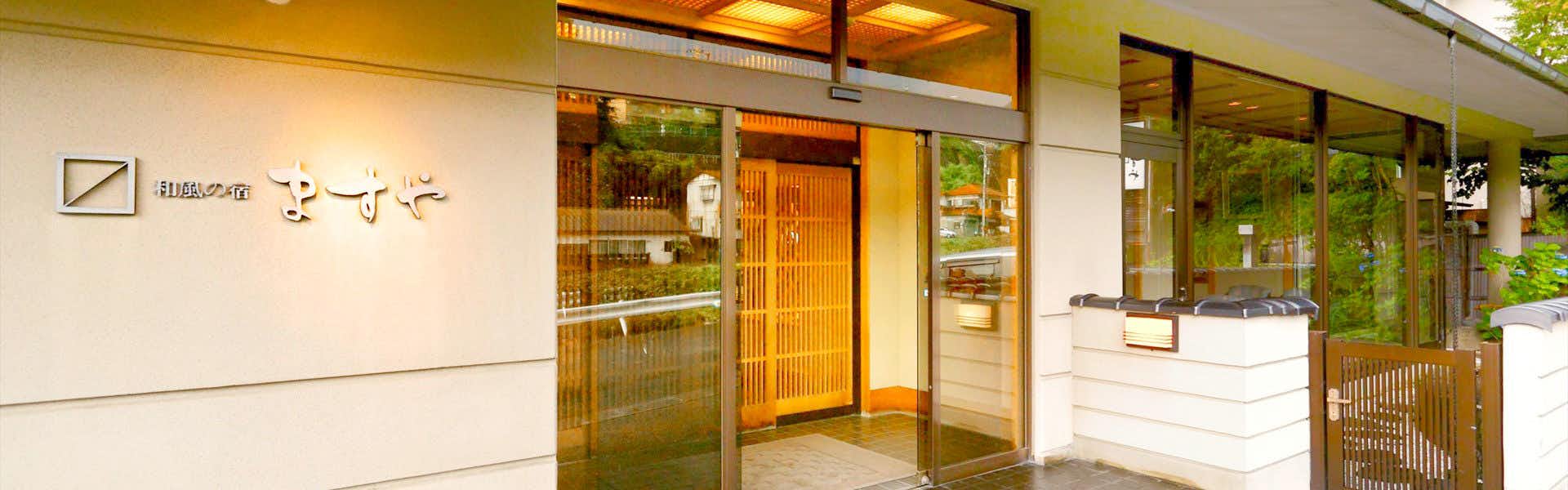 Yudanaka Onsen Wafu no Yado Masuya glass-front lodging entrance beside green garden trees