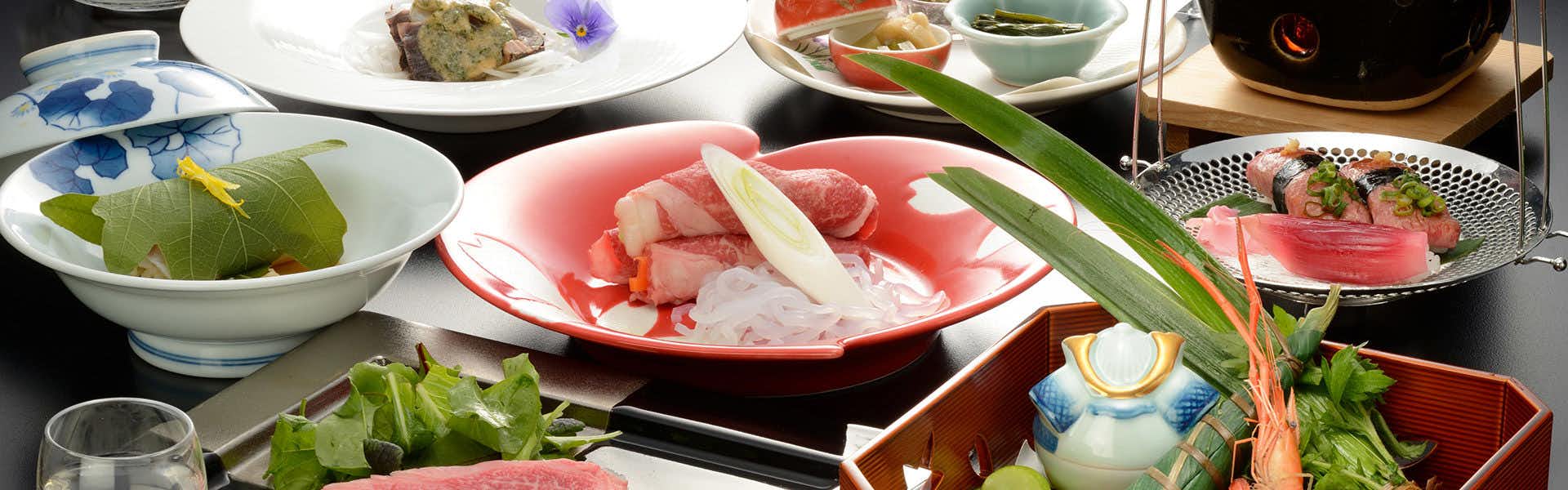 Akayu Onsen Mori no Yu Multiple bowls and plates containing greens and sliced pink food with bamboo decoration and additional covered vessels displayed