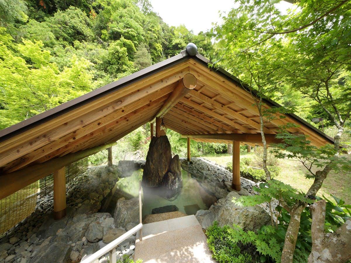 Valley Villa Mochinoki with a private open-air stone bath beneath a timber roof.