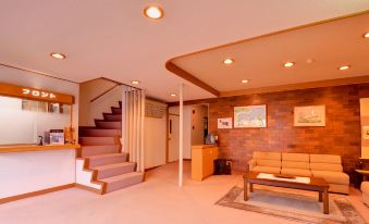 A lobby with a reception counter, staircase, and sofa.