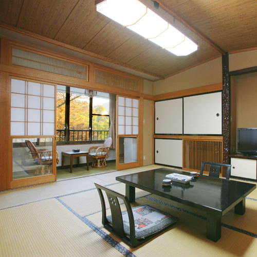 A tatami guest room with a dark low table and a window-side sitting area.