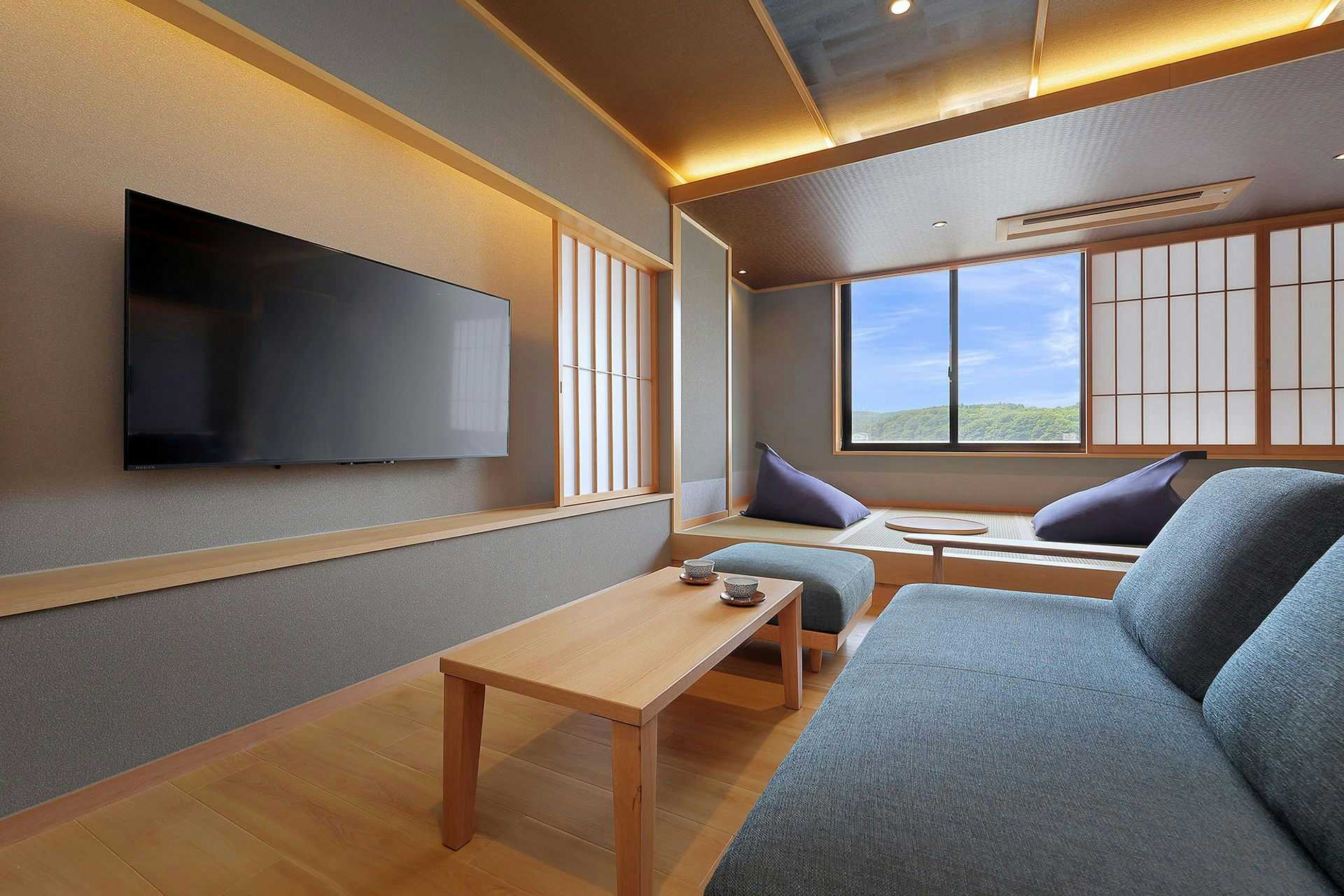 Ryokan Sanjiro with a contemporary sitting room with gray sofa and television.