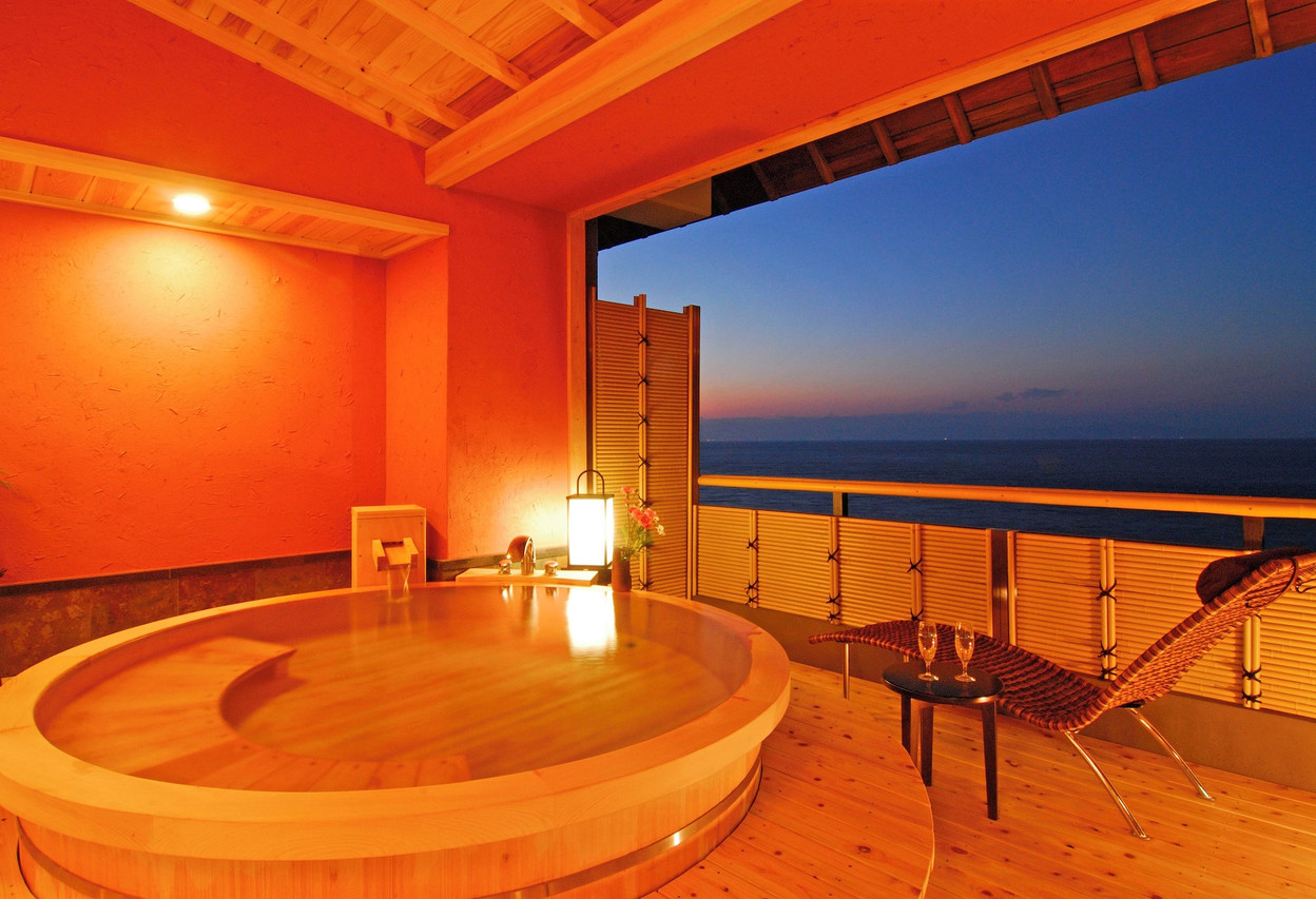 Round wooden bath with an evening ocean view.