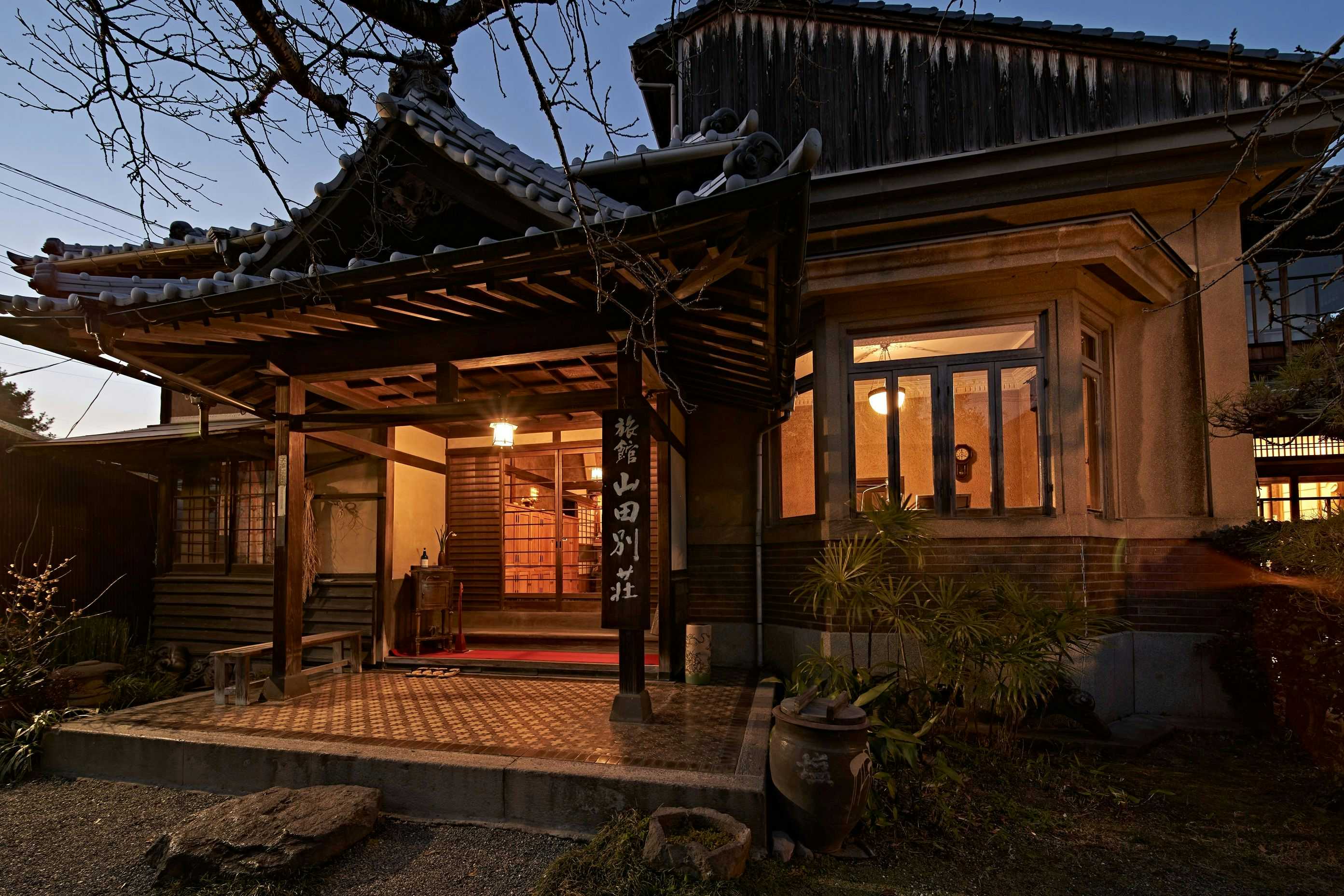Yamada Bessou with an illuminated wooden entrance beneath a dark tiled roof.
