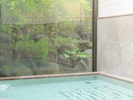 Bettei Ichika with a pale indoor bath overlooking a compact green garden.