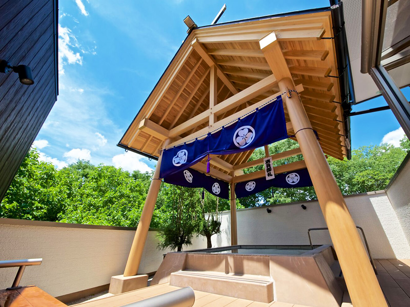 A timber bath pavilion beneath a blue entrance curtain.
