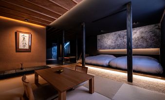 Dark Japanese-style bedroom with a low table, tatami floor, and wide bed platform.