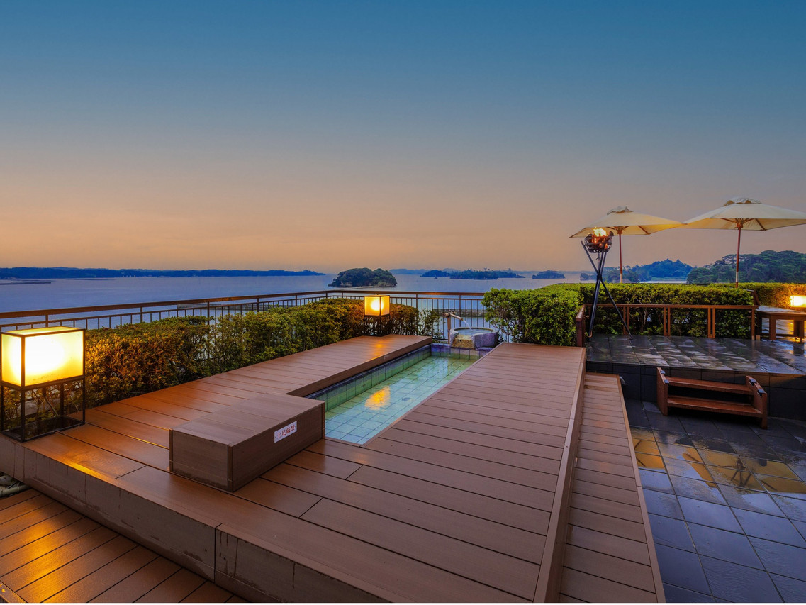 A rooftop terrace with a narrow open-air bath overlooking the bay at dusk.