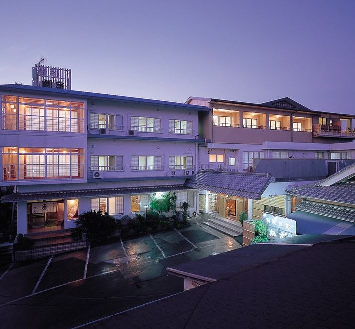 A multi-story lodging building illuminated in the evening.