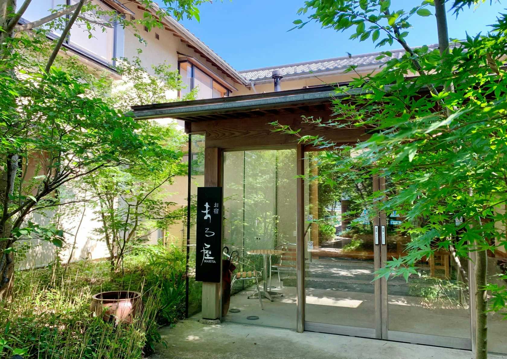 Oyado Maruya with the glass entrance framed by dense green garden trees.
