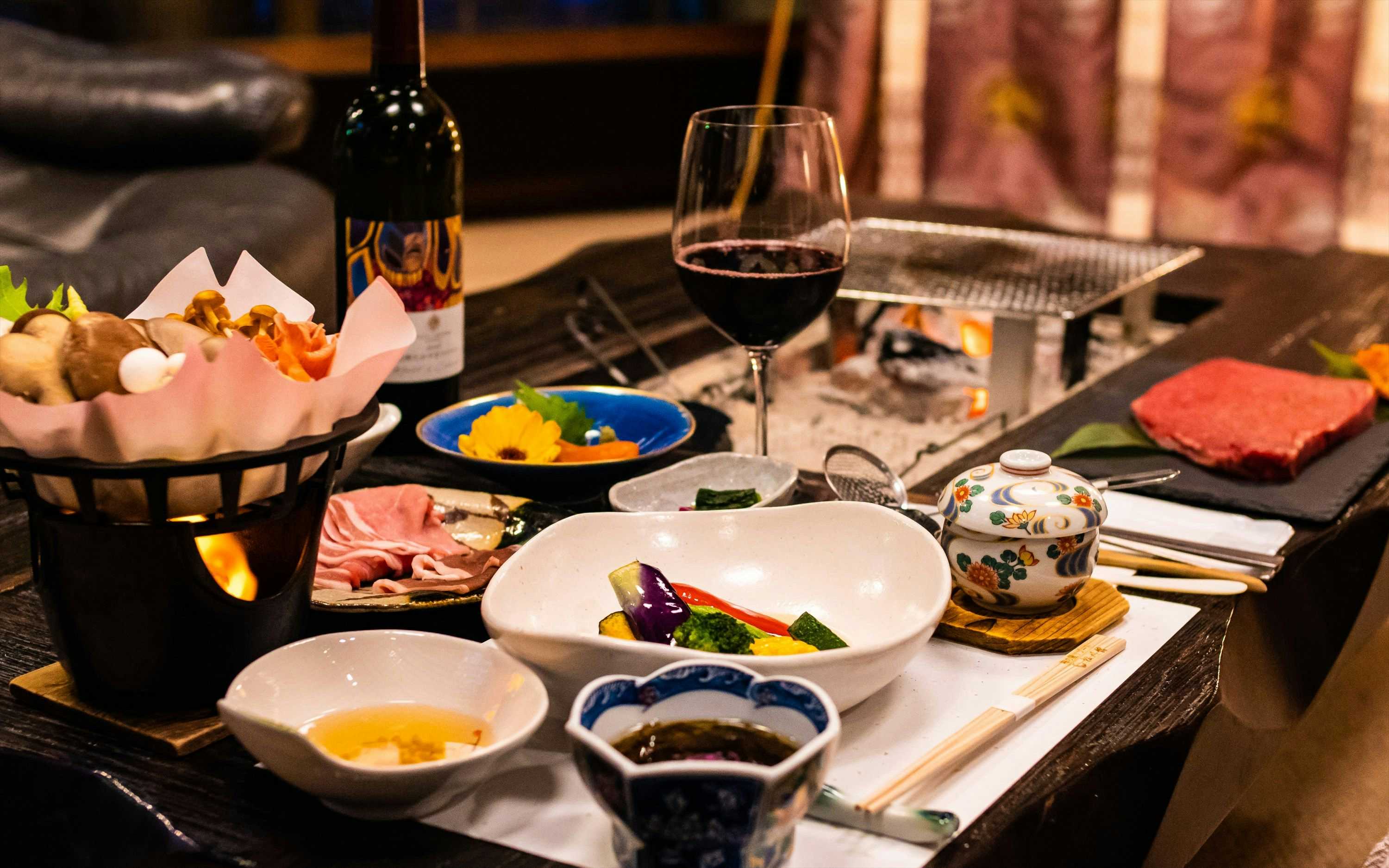Umeno-ya Resort Matsukawa-kan with a Japanese dinner arranged beside a tabletop grill and wine.