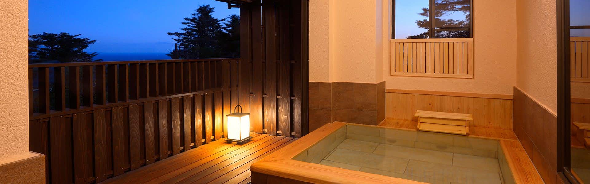 Izu Kogen Syuhari with a rectangular wooden tub, railings, lanterns, and dark blue sky