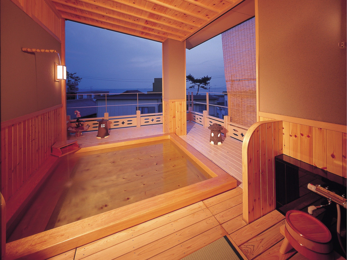 A covered wooden bath terrace overlooking the evening sky.