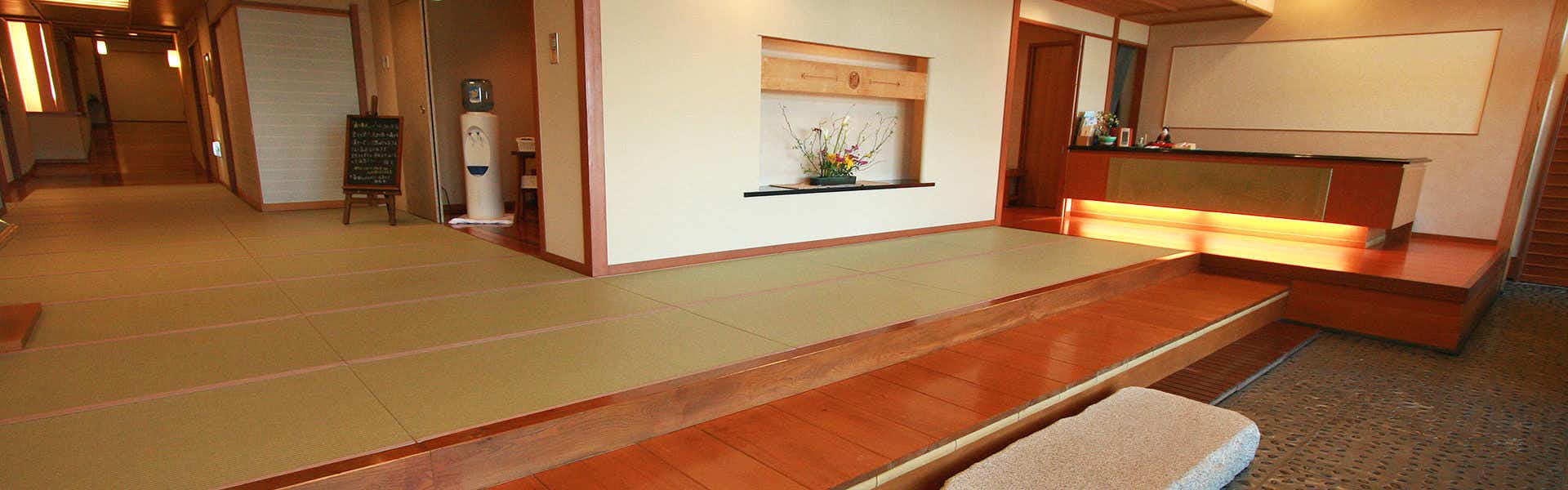 Soshin no Yado Oishiya reception entrance with a flower arrangement and curved floor guide