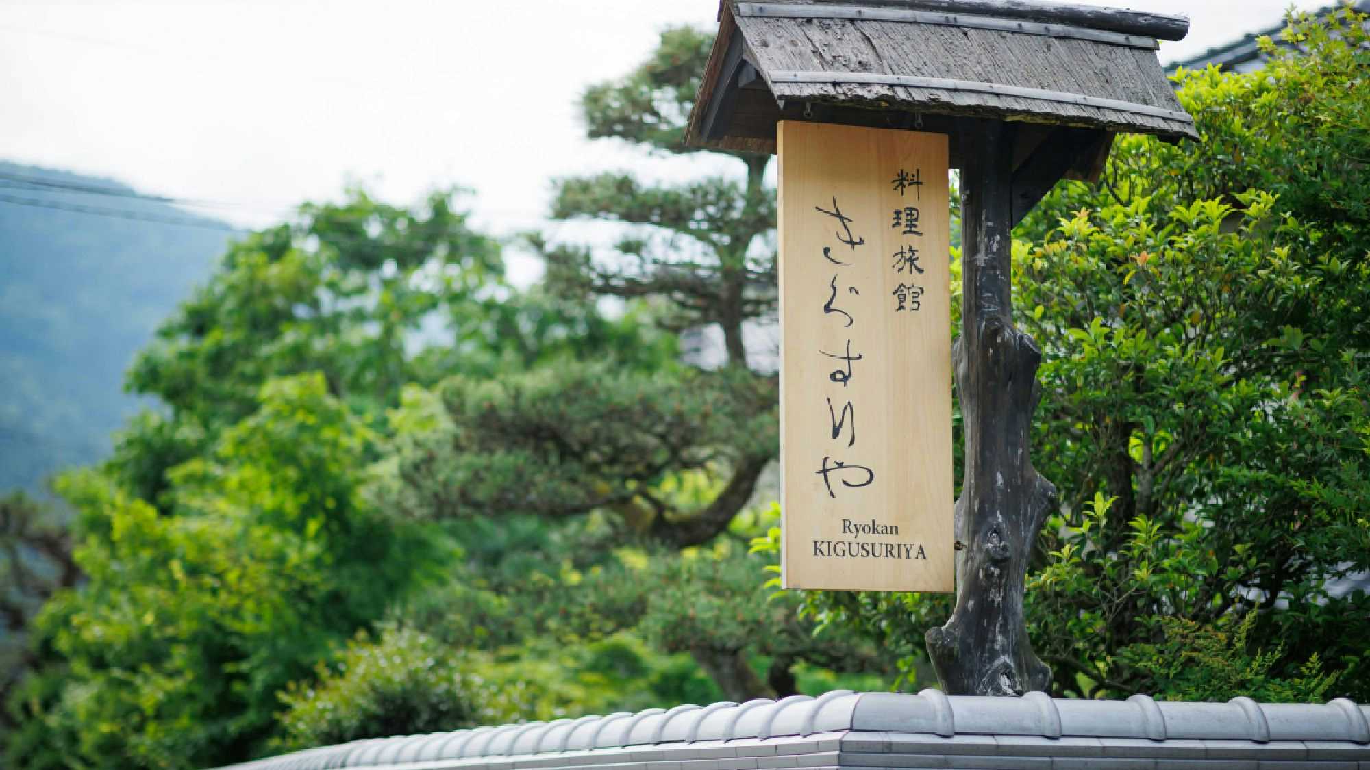 Cuisine Ryokan Kigusuriya with a wooden entrance sign beside sculpted pine branches.