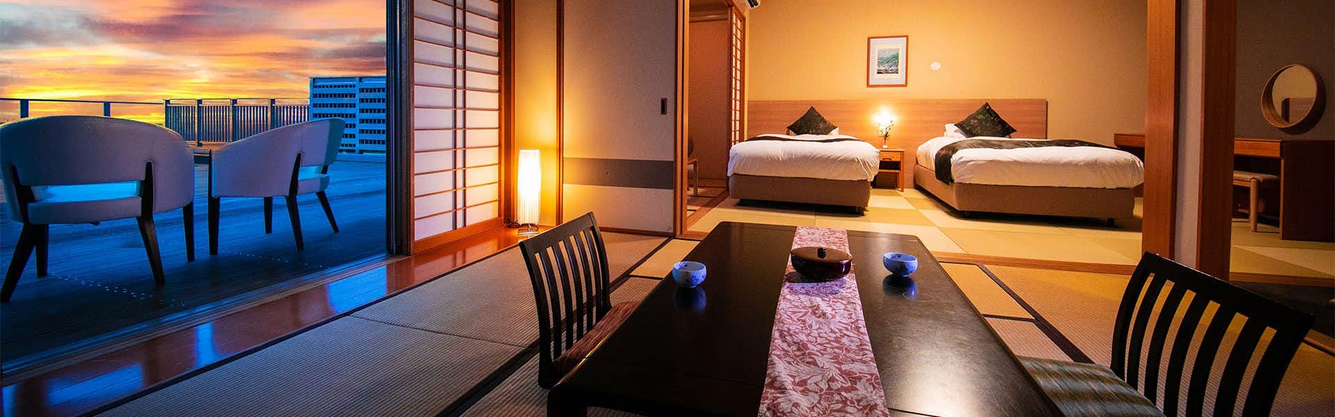Watari Onsen Tori no Umi with a guest room balcony facing the sea at sunset.