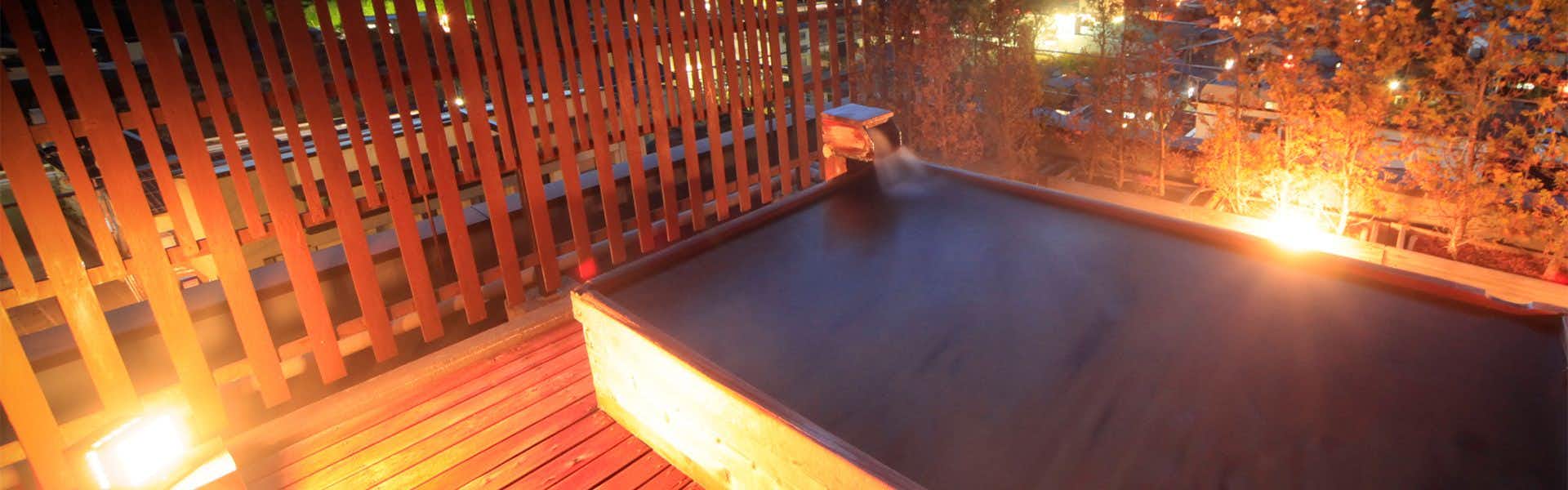 Hotel Tsubakino Wooden deck platform with vertical railings overlooking dark basin structure.