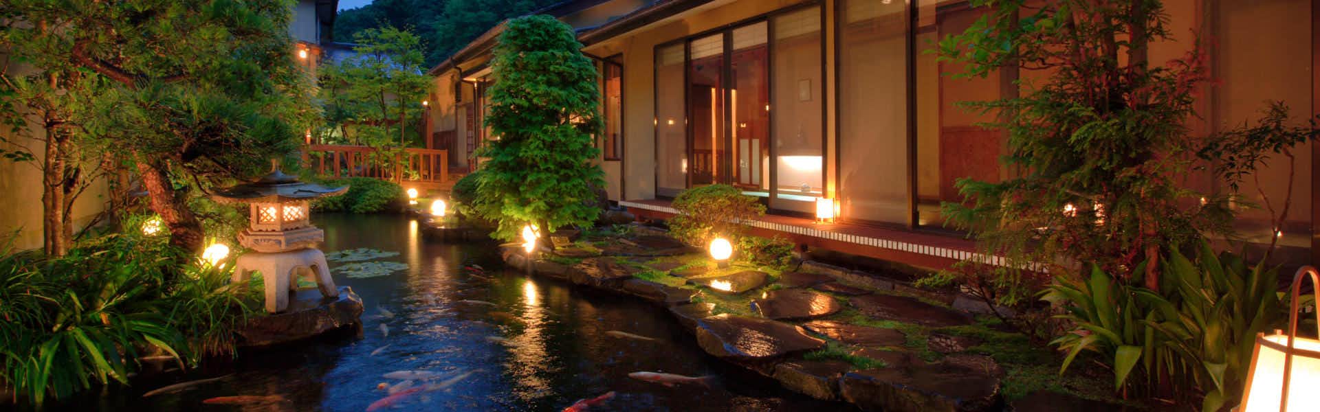 -Syunsai no Yado- Ryokusuitei illuminated courtyard garden with a pond and guest rooms at night