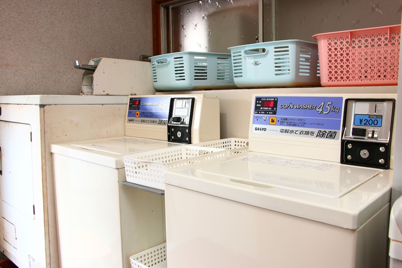 Two coin-operated washing machines beneath laundry baskets.