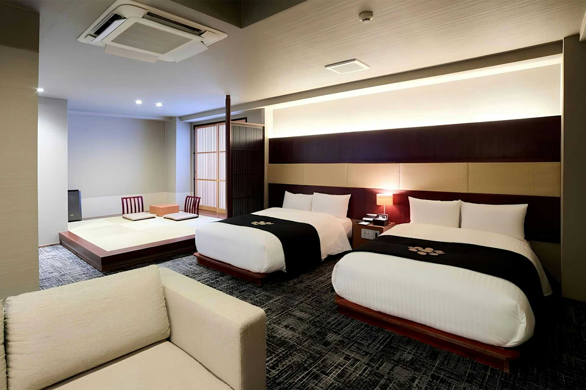Ryotei Matsuya Honkan Suizenji with a spacious modern twin bedroom with pale sofa.