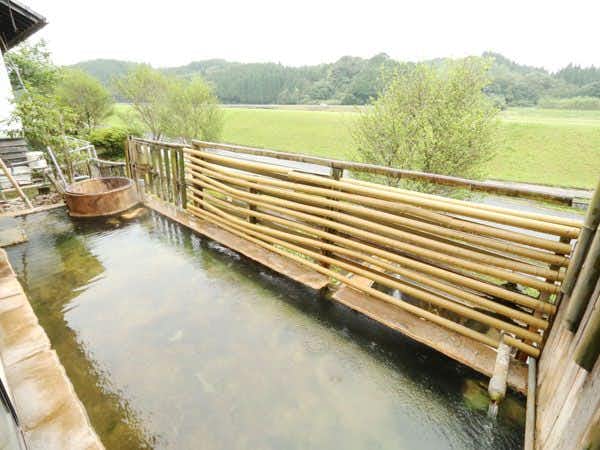 Yunoo Onsen Irori no Yado Ryokan Hayamizusou with an outdoor mineral bath overlooking green fields and trees.