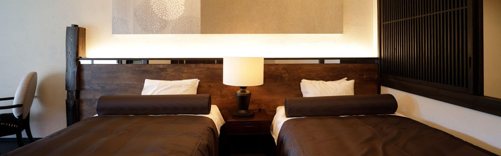 Umi no Hotel Isaba with a dark twin bedroom framed by warm wood and soft lighting.