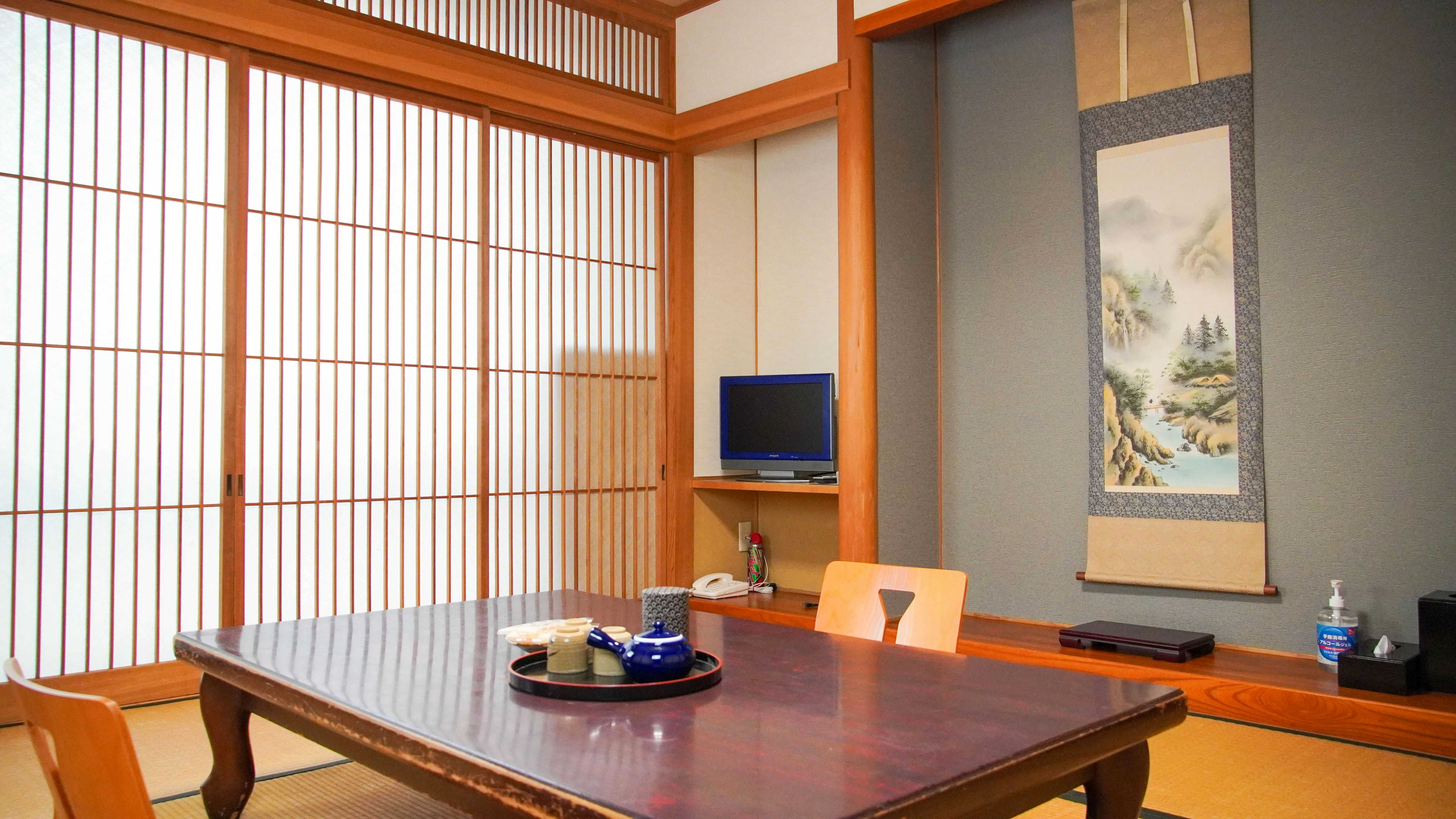 Ryokan Omasa with a warm tatami room with low table and painted alcove.