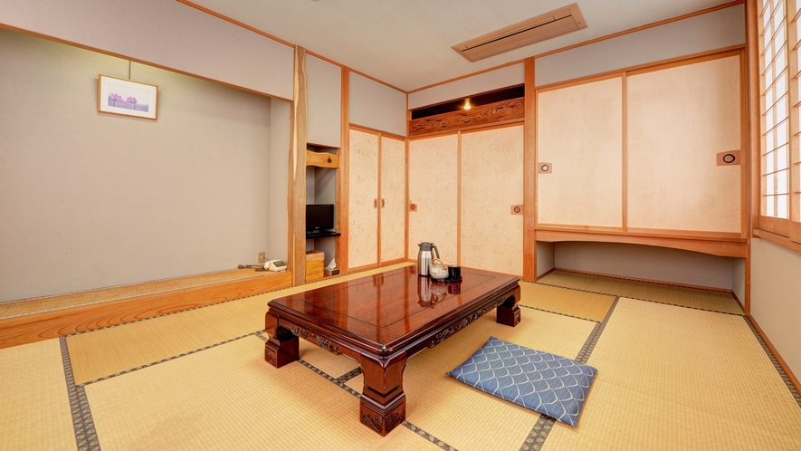 A Japanese guest room with a polished low table, floor cushions, and sliding doors.