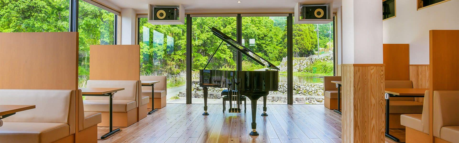 Yufuin Sumika Black grand piano, wooden flooring, glass windows framing forest and hillside landscape