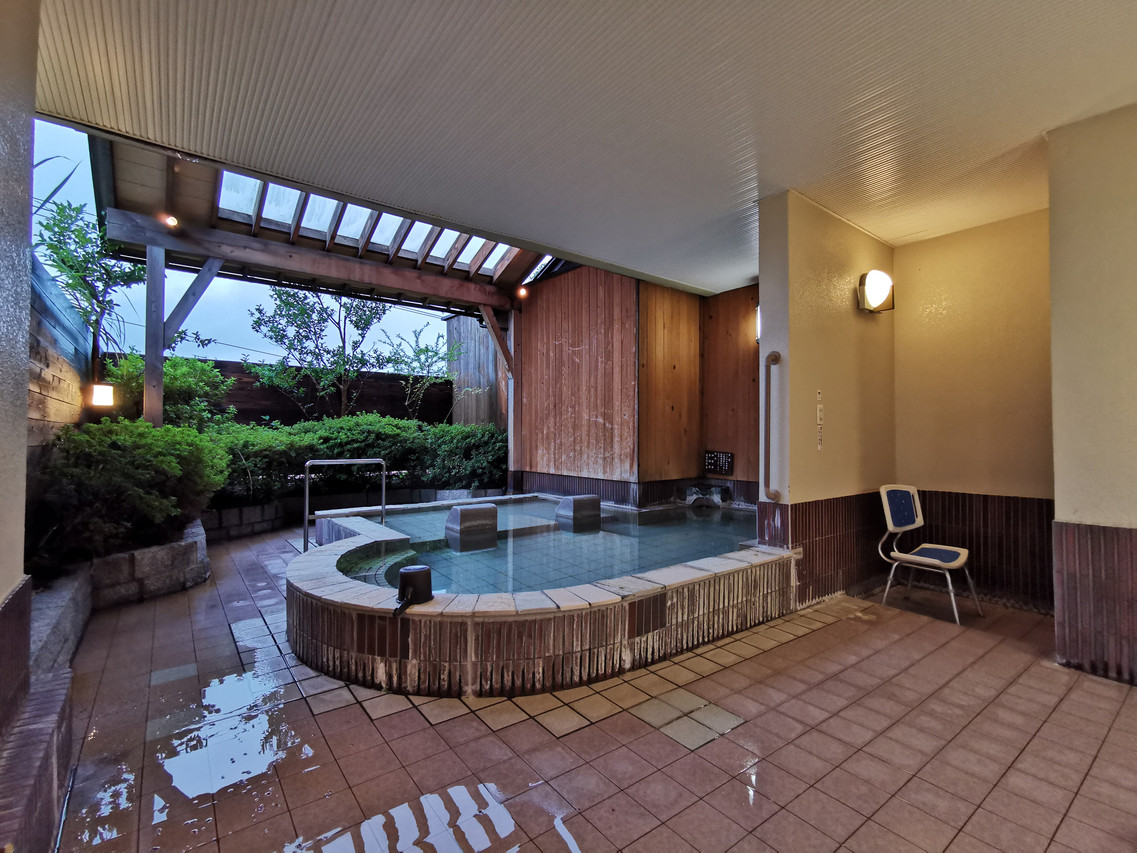 Covered outdoor bath beside a landscaped garden.