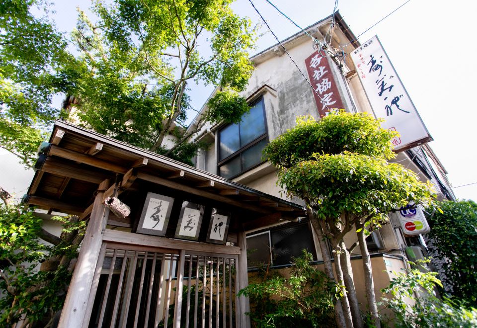 The ryokan entrance framed by leafy trees.