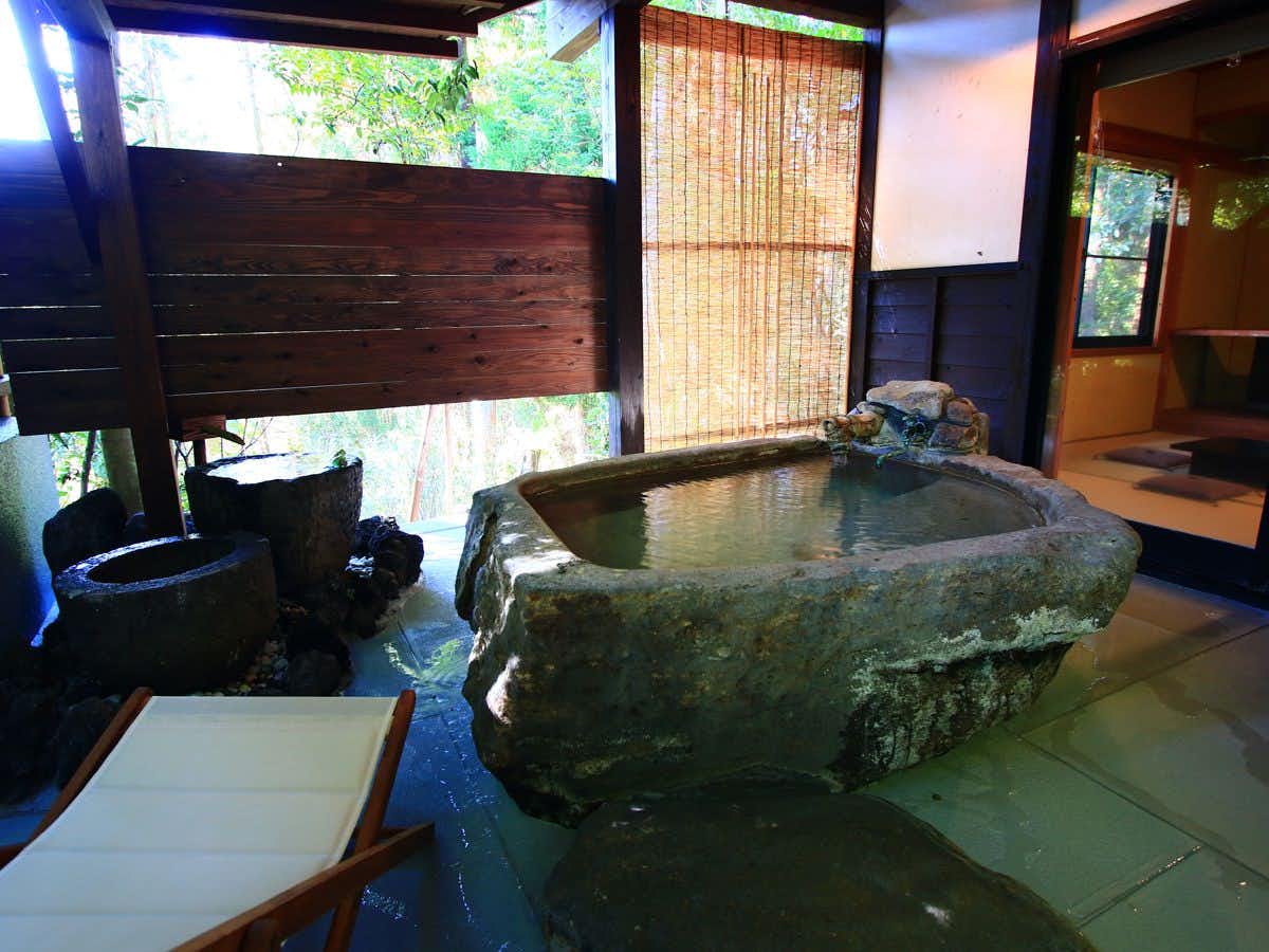 Yamakawa ZENZO a stone indoor bath enclosed by dark wooden screens.