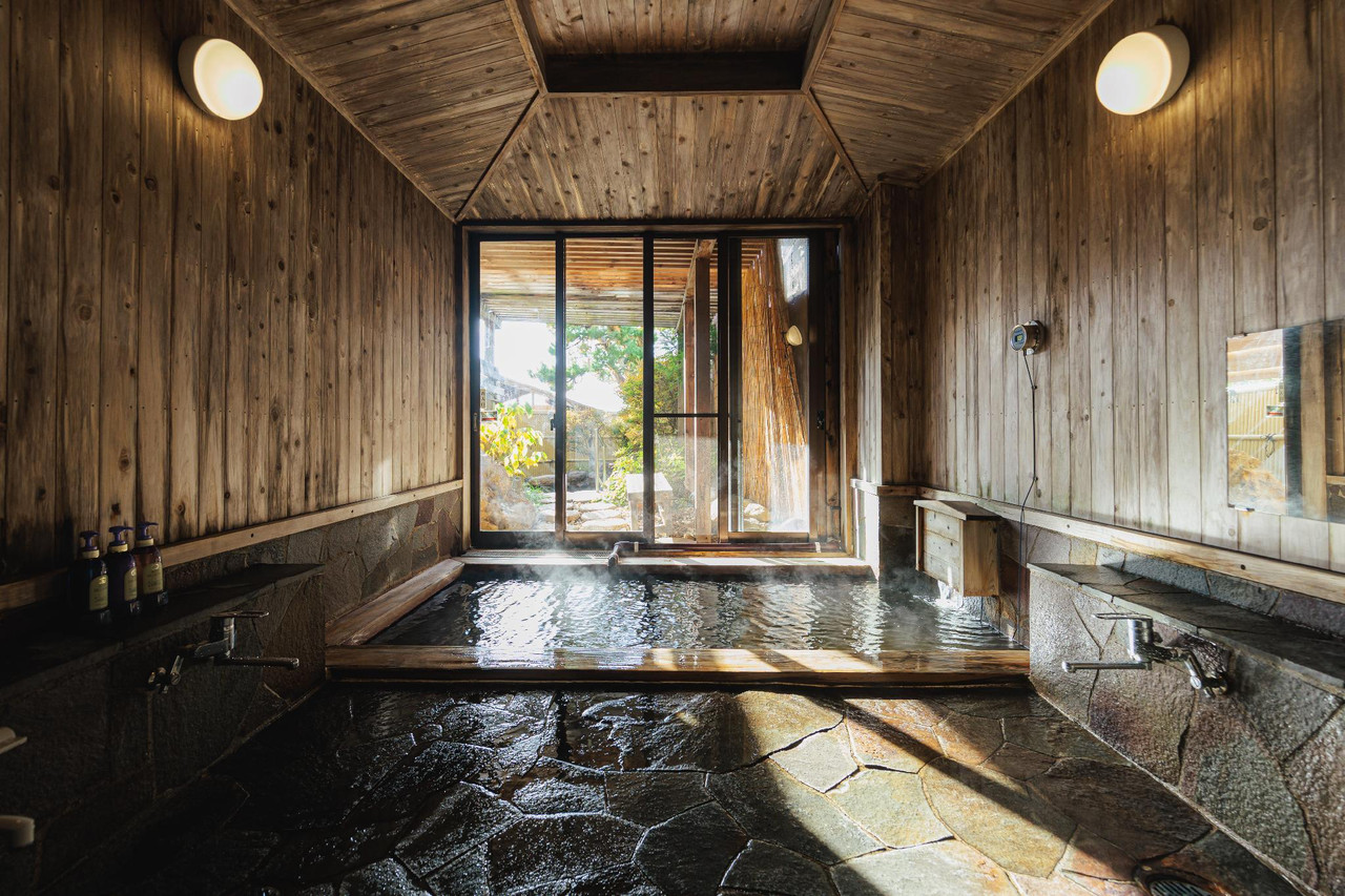 A wood-lined bath opens toward the outdoors through a central window.