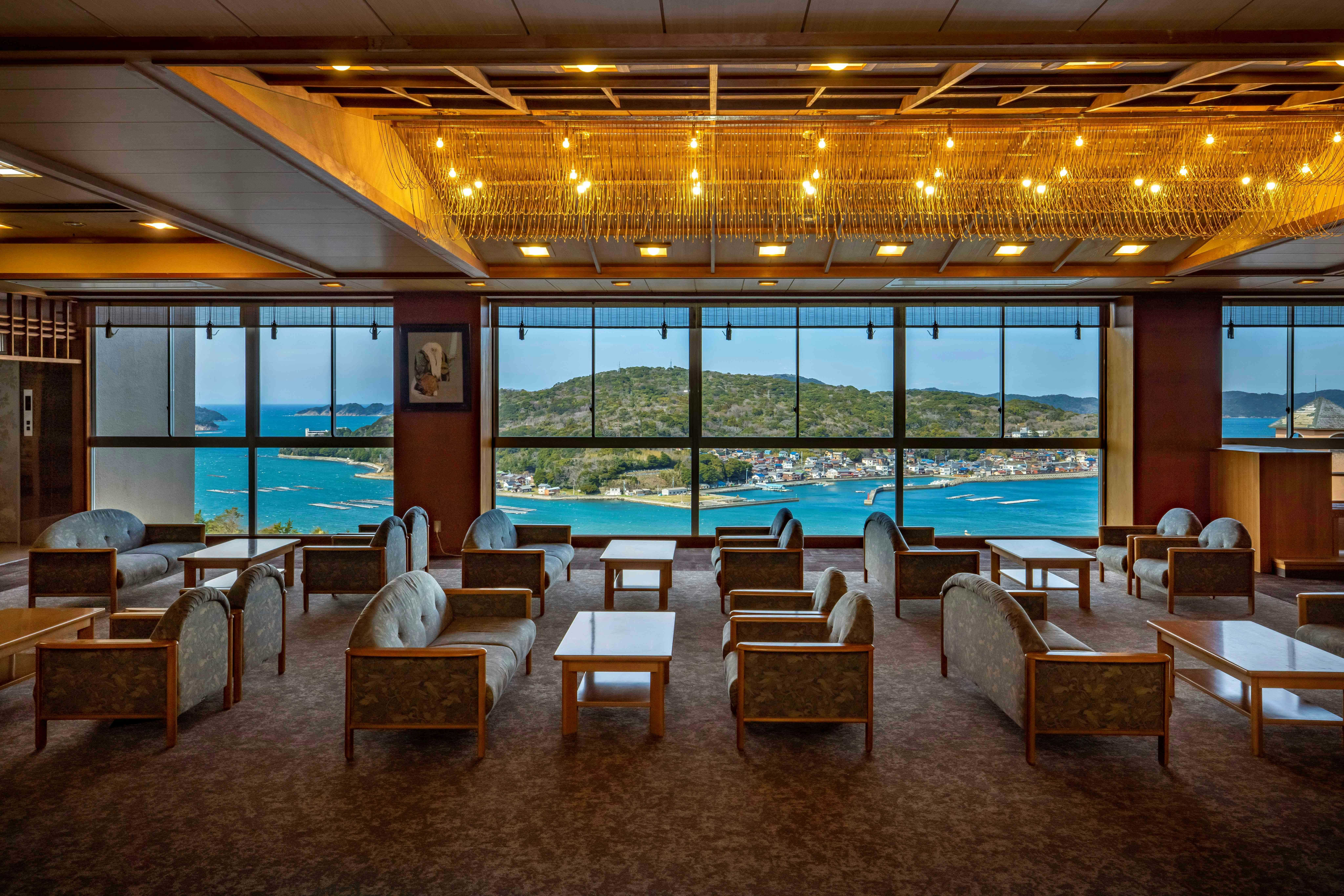 Arashima Onsen Yumoto Ama no Shima with a spacious lounge lined with floor-to-ceiling ocean windows.