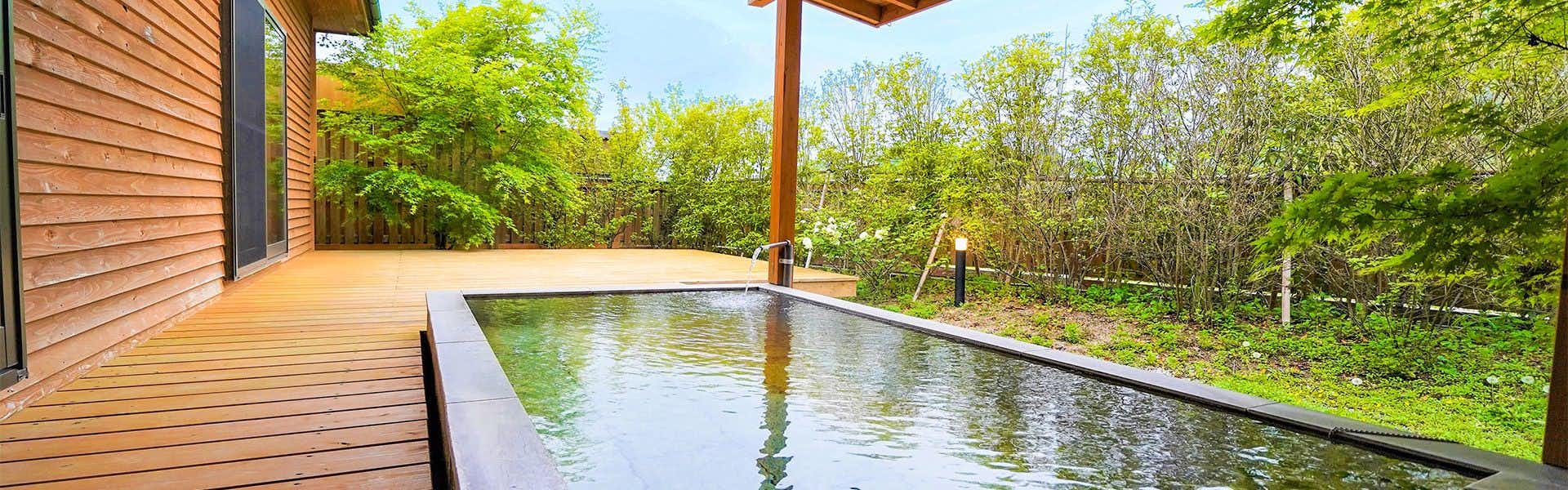 Yufuin Sumika Rectangular water feature with concrete edge, wooden post, forest foliage beyond