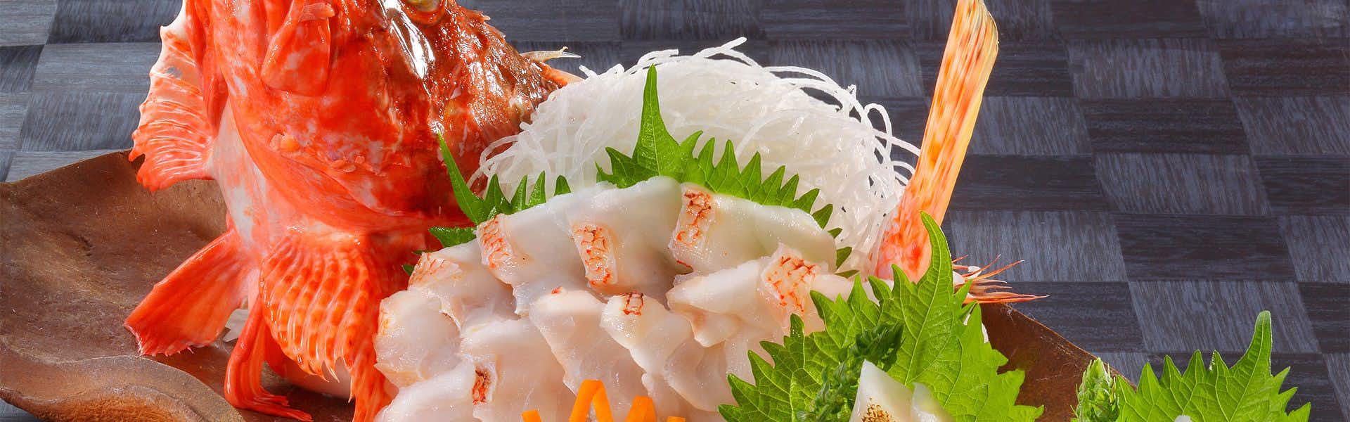 Yusuitei Isagoya Sliced seafood arranged with white daikon strands and shiso leaves on dark plate, reddish seafood components visible at edges