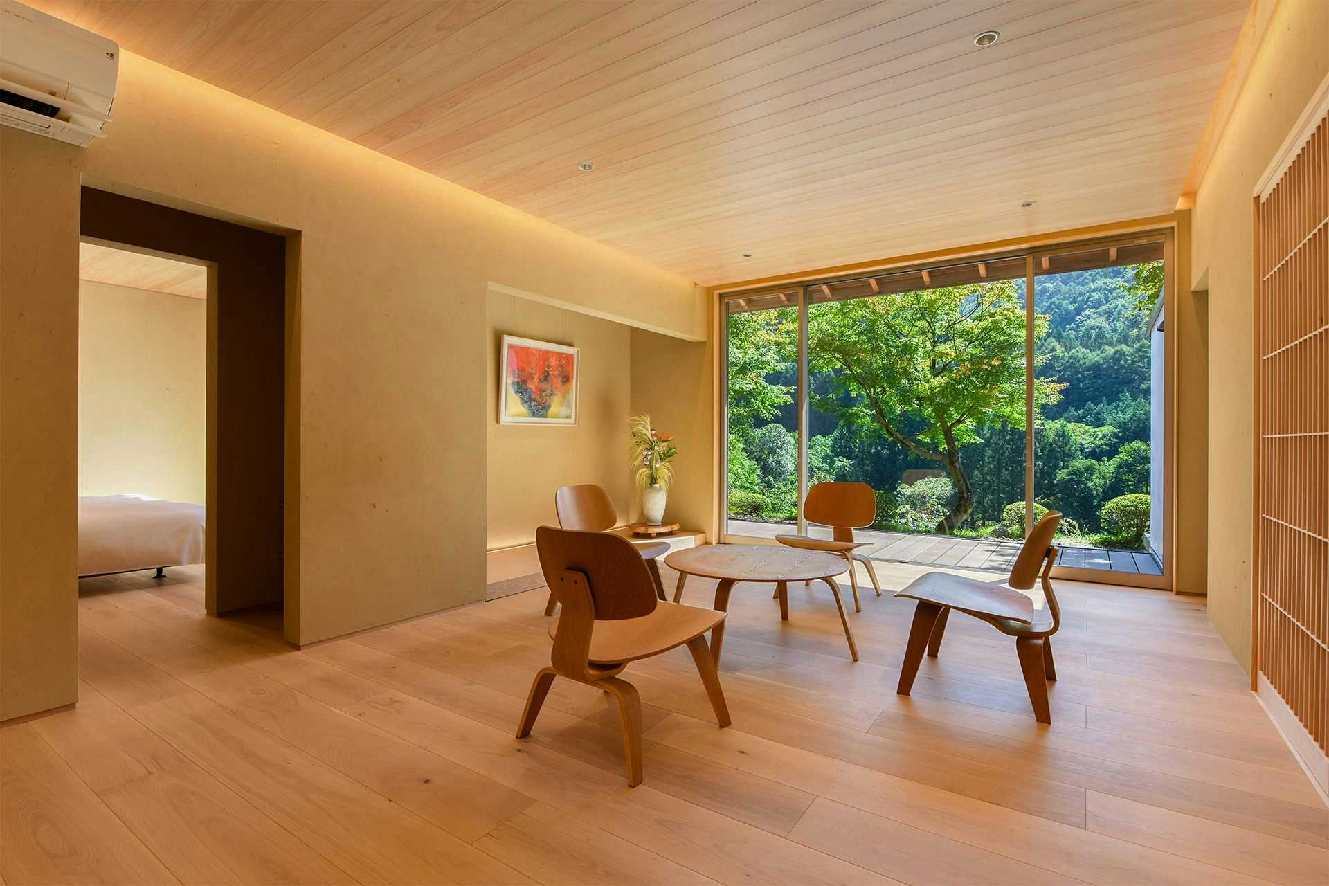 Kawaba Onsen Clear Stream Village Kinshu Sanso with a bright lounge with pale wood walls and forest views.