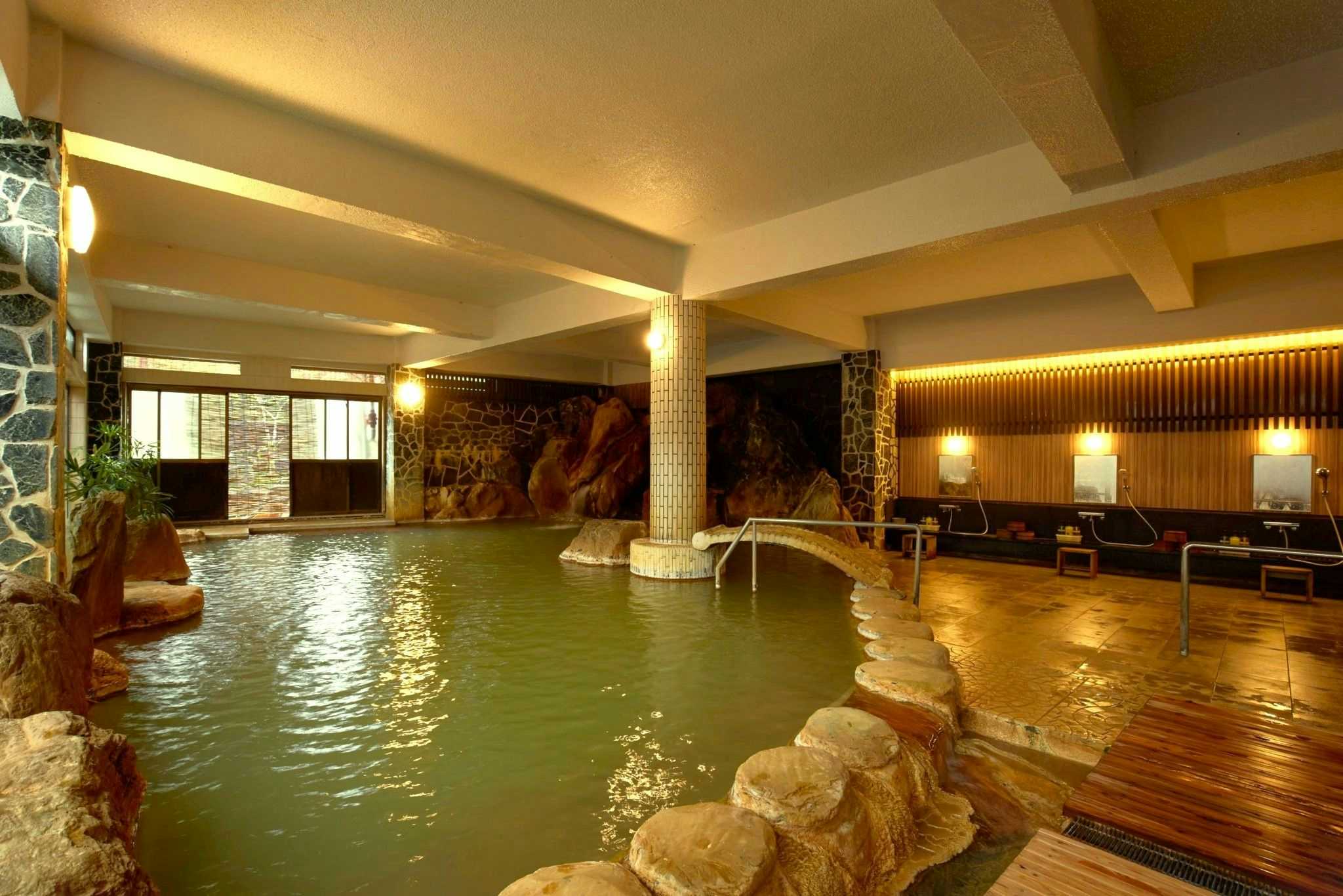 Myoken Onsen Nemu with a broad indoor mineral bath supported by pale columns.