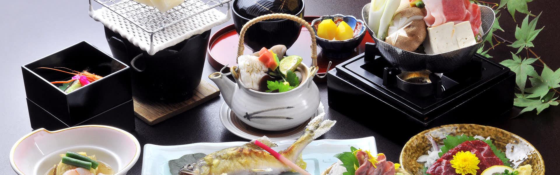 Hitoyoshi Ryokan with a colorful Japanese dinner arranged across black lacquer trays.