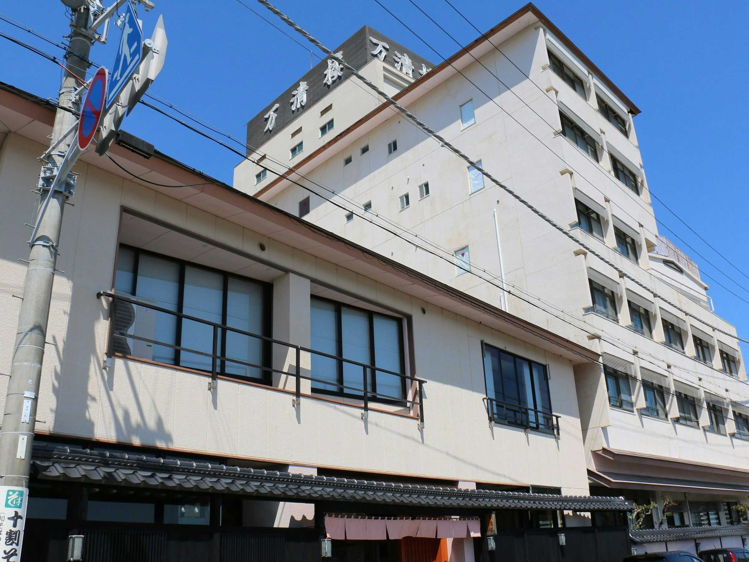 Manseirou with a white street-facing facade rising beneath a clear blue sky.